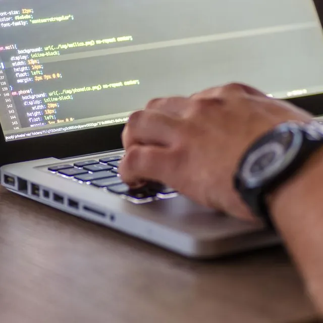 Hands typing code on a laptop keyboard