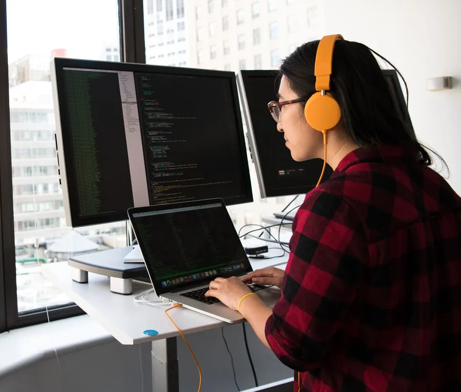 Developer working across two monitors and a laptop, code on every screen